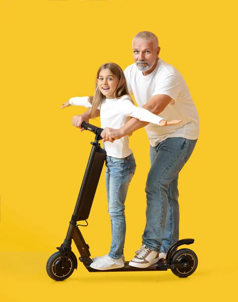Klein Meisje Met Haar Grootvader Elektrische Scooter Gele Achtergrond — Stockfoto
