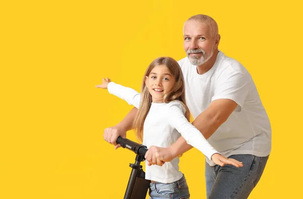 Niña Con Abuelo Scooter Eléctrico Sobre Fondo Amarillo —  Fotos de Stock