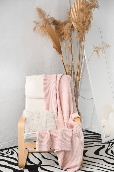 Hafif duvarın yanında pembe ekose koltuklu.