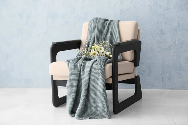Kol sandalyesi şık ekoseli ve ışık duvarının yanında çiçekler