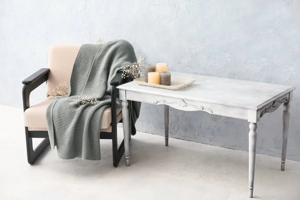 Ekoseli koltuk, çiçekler, masa ve ışık duvarının yanındaki mumlar.