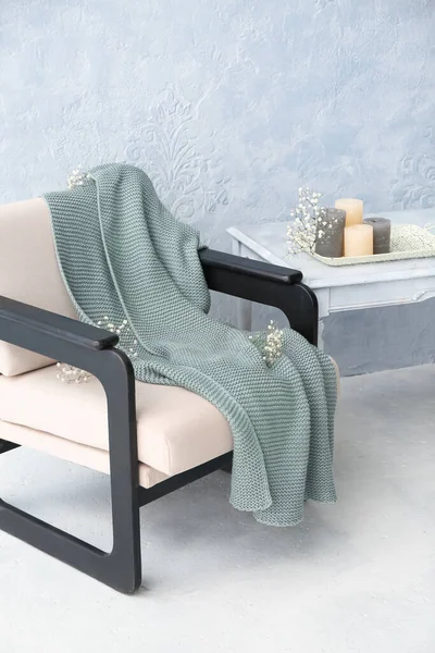 Ekoseli koltuk, çiçekler, masa ve ışık duvarının yanındaki mumlar.