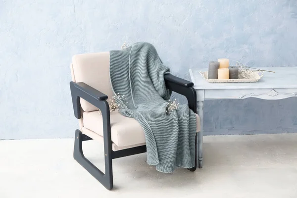 Ekoseli koltuk, çiçekler, masa ve ışık duvarının yanındaki mumlar.