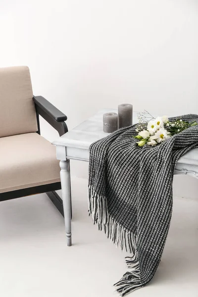 Ekoseli masa, çiçekler, mumlar ve ışık duvarının yanındaki koltuk.