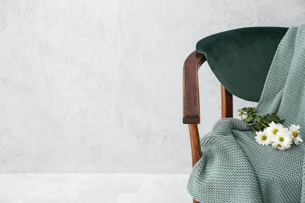 Kol sandalyesi şık ekoseli ve ışık duvarının yanında çiçekler