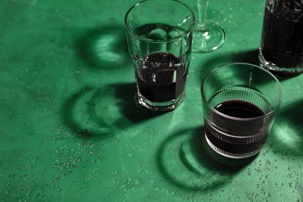 Yeşil arka planda alkollü farklı bardaklar.