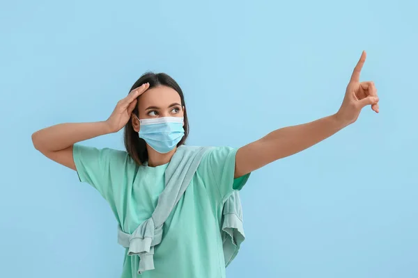 Mujer Joven Con Máscara Médica Señalando Algo Sobre Fondo Azul —  Fotos de Stock