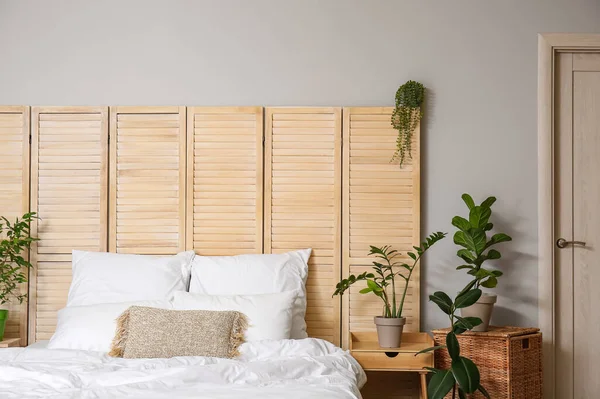 Ev bitkileri ve katlanan ekran ile aydınlık yatak odasının içi