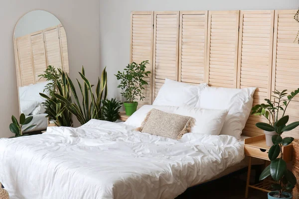 Ev bitkileri ve katlanan ekran ile aydınlık yatak odasının içi