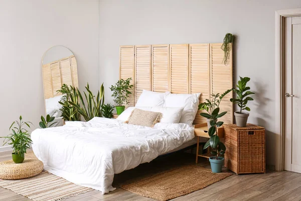 Ev bitkileri ve katlanan ekran ile aydınlık yatak odasının içi