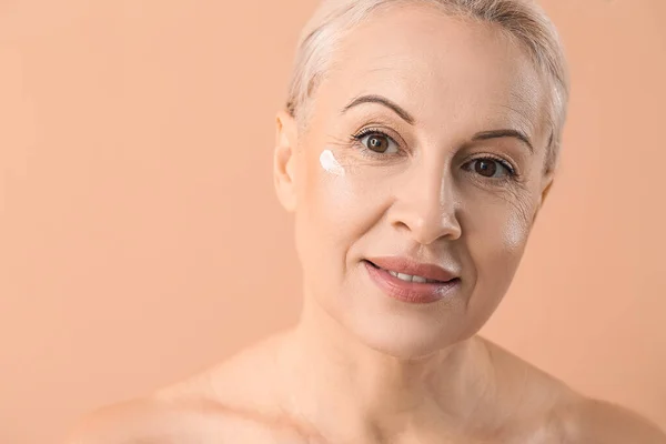 Ältere Blonde Frau Mit Gesichtscreme Auf Beigem Hintergrund Nahaufnahme — Stockfoto