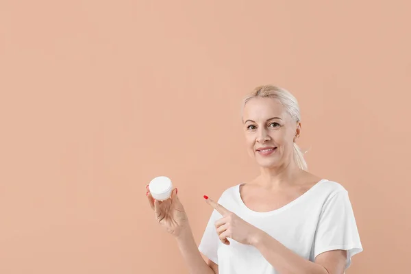 Mature Blonde Woman Pointing Jar Cream Beige Background — Stock Photo, Image
