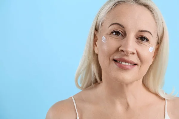 Ältere Blonde Frau Mit Gesichtscreme Auf Blauem Hintergrund Nahaufnahme — Stockfoto