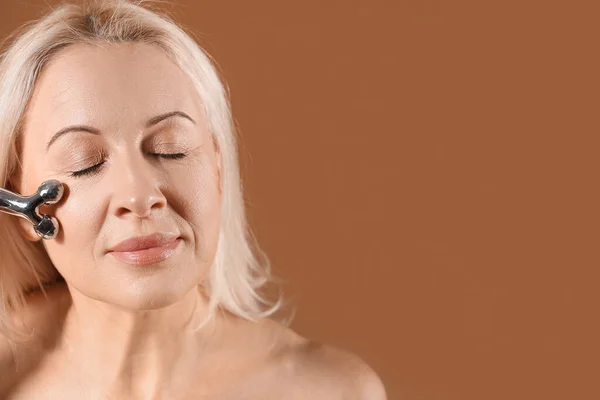 Mature Blonde Woman Facial Massage Tool Brown Background Closeup — Stock Photo, Image