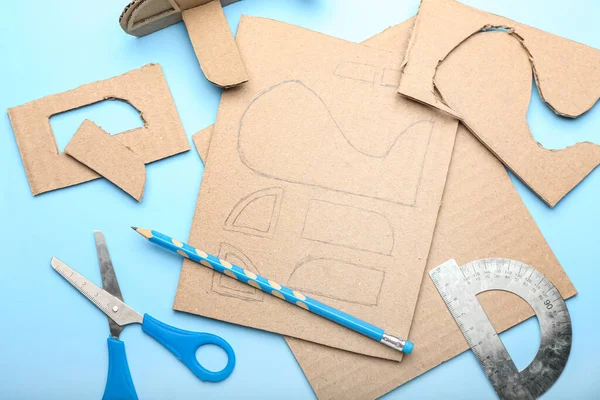 Mavi arka planda karton uçak oyuncağı yapmak için malzemeler