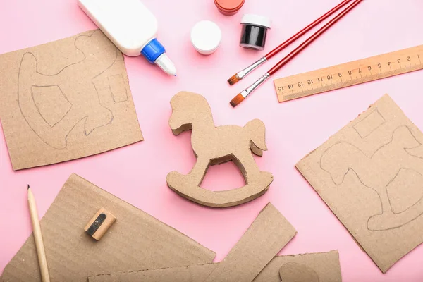 Karton sallanan atı pembe arka planda yapmak için malzemeler