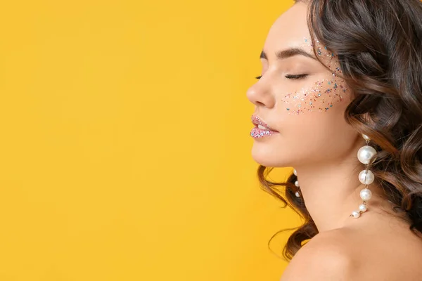 Mooie Jonge Vrouw Met Glitters Haar Gezicht Tegen Gele Achtergrond — Stockfoto