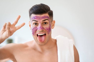 Parlak maskeli yakışıklı adam banyoda zafer jesti gösteriyor.