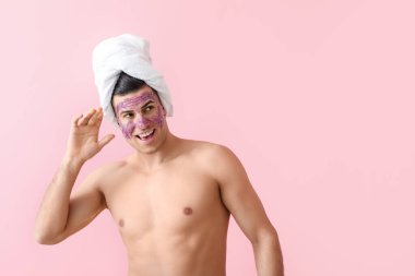 Pembe arka planda parlak maskeli ve havlusu olan yakışıklı bir adam.