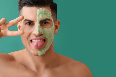 Kabarcık maskeli yakışıklı yeşil arka planda zafer jesti gösteriyor.