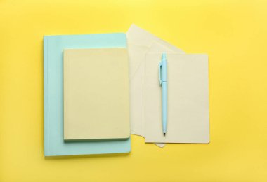 Sarı arka plan daki defterler ve kalem, üst görünüm