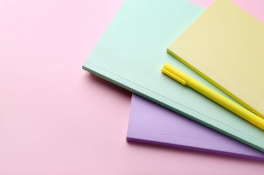 Pembe arka planda defterler ve kalemler