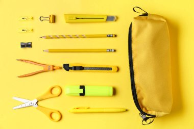 Sarı arka planda okul kırtasiyesi olan kalem kutusu, üst görünüm