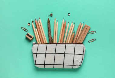 Turkuaz arka planda okul kırtasiyesi olan kalem kutusu, üst görünüm