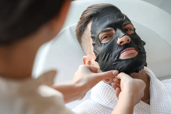 Cosmetologist Applying Sheet Mask Young Man Face Salon Closeup — Stock Photo, Image