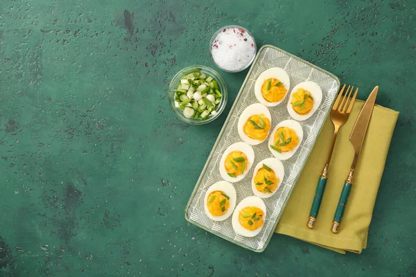 Doldurulmuş yumurta, yeşil soğan, tuz, çatal bıçak takımı ve yeşil arka planda peçete. Paskalya kutlaması