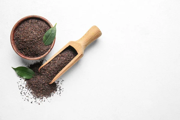 Beyaz arka planda kuru çay yaprakları ile kase ve kepçe, üst görünüm