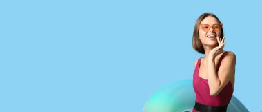 Mavi arka planda şişirilebilir yüzüklü, metin için yeri olan güzel genç kadın.