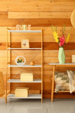 Üzerinde güzel gladiolus çiçekleri olan vazo ahşap duvarın yanında.