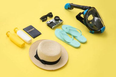 Dalış maskeli plaj aksesuarları ve sarı arka planda fotoğraf makinesi.