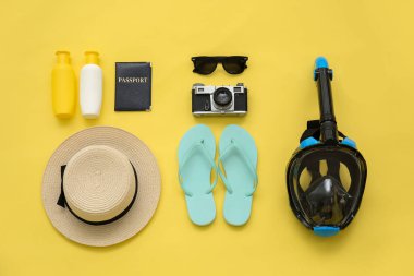 Dalış maskeli plaj aksesuarları ve sarı arka planda fotoğraf makinesi.