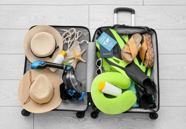 Kadın plaj aksesuarları, bağışık pasaport ve beyaz ahşap arka planda şnorkelli maske.