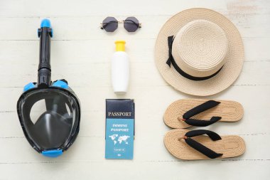 Beyaz ahşap arka planda şnorkel maskeli ve bağışıklık pasaportlu kadın plaj aksesuarları.