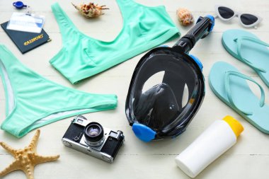 Dalış maskeli ve beyaz ahşap arka planda bağışıklık sertifikalı kadın plaj aksesuarları.