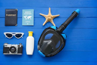 Mavi ahşap arka planda şnorkel maskeli ve bağışıklık pasaportlu plaj aksesuarları.