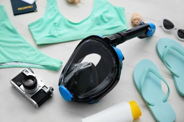 Dalış maskeli kadın plaj aksesuarları ve beyaz ahşap arka planda fotoğraf makinesi.