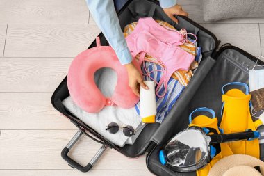 Kadın valizinde güneş kremi taşıyor.