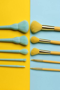 Renk arkaplanındaki farklı makyaj fırçaları