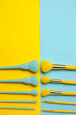 Renk arkaplanındaki farklı makyaj fırçaları