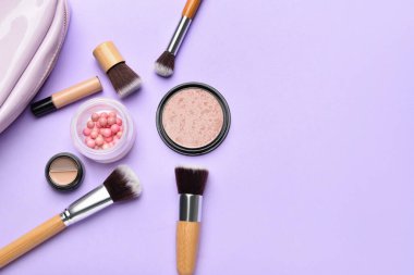 Mor arka planda makyaj fırçaları ve kozmetik ürünleri