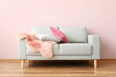 Oda duvarının yanında yastıklı ve ekoseli modern kanepe.