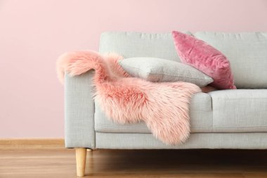 Oda duvarının yanında yastıklı ve ekoseli modern kanepe.