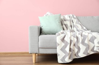 Oda duvarının yanında yastıklı ve ekoseli modern kanepe.