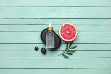 Renkli ahşap arka planda greyfurt ve gerekli yağın yarısıyla kompozisyon