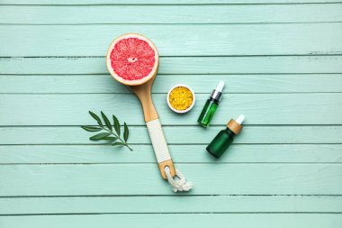 Renkli ahşap arka planda greyfurt, deniz tuzu ve gerekli yağ şişelerinin yarısıyla kompozisyon