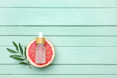 Renkli ahşap arka planda greyfurt ve gerekli yağın yarısıyla kompozisyon